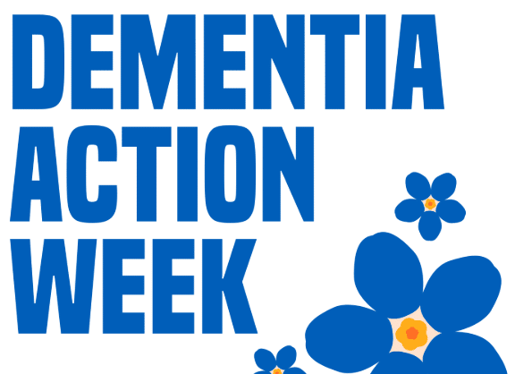 Photo of two white women outside with trees in the background. stood next to each other and smiling towards the camera. The woman on the left has long hair and the woman on the right has a short bobbed hair cut.