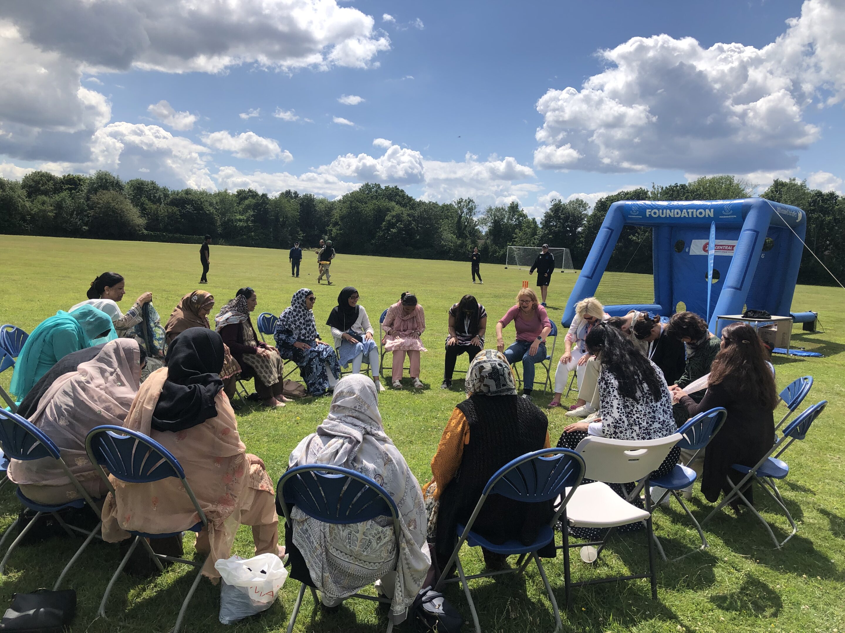 Photo of two white women outside with trees in the background. stood next to each other and smiling towards the camera. The woman on the left has long hair and the woman on the right has a short bobbed hair cut.