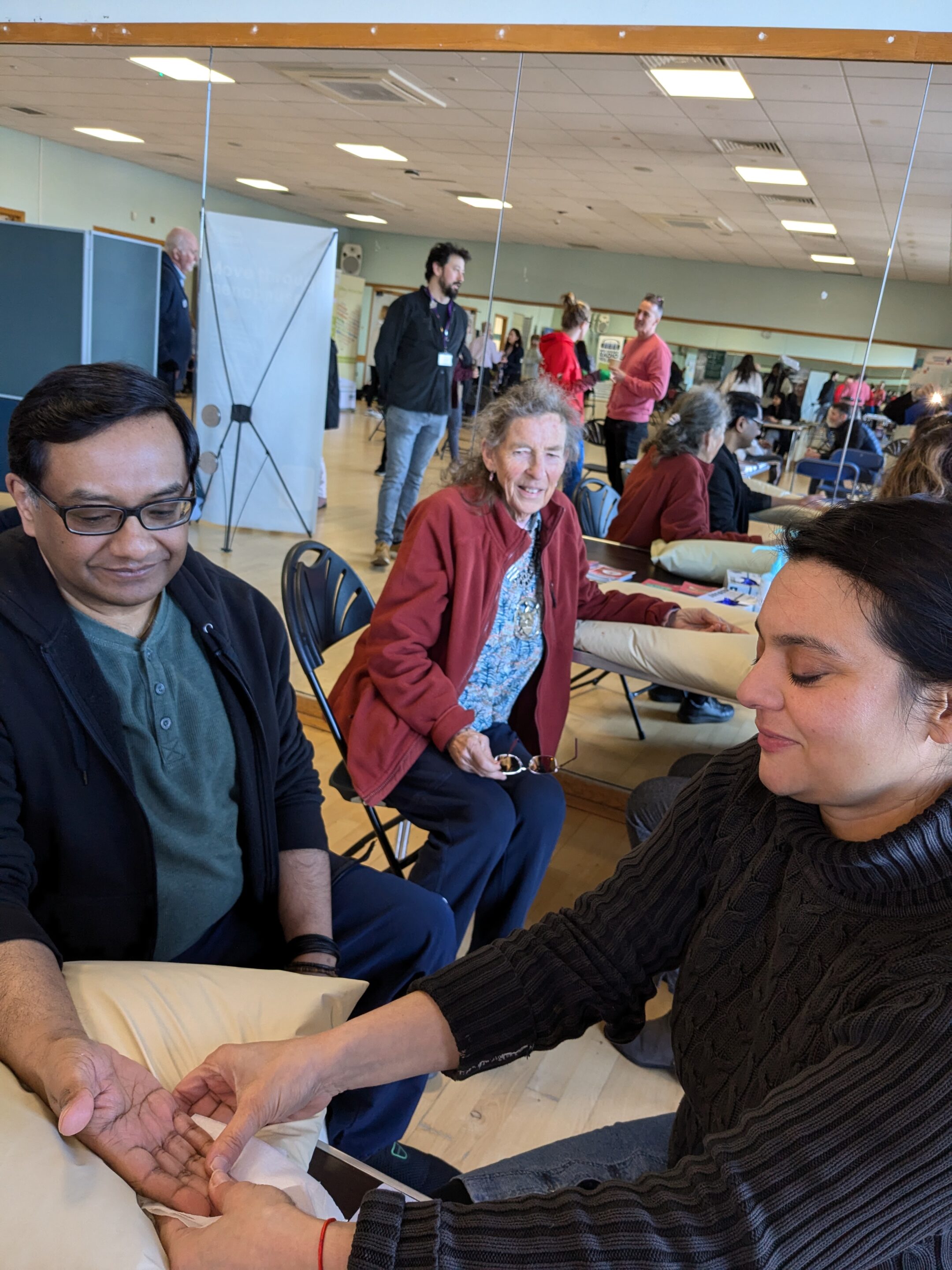 Photo of two white women outside with trees in the background. stood next to each other and smiling towards the camera. The woman on the left has long hair and the woman on the right has a short bobbed hair cut.